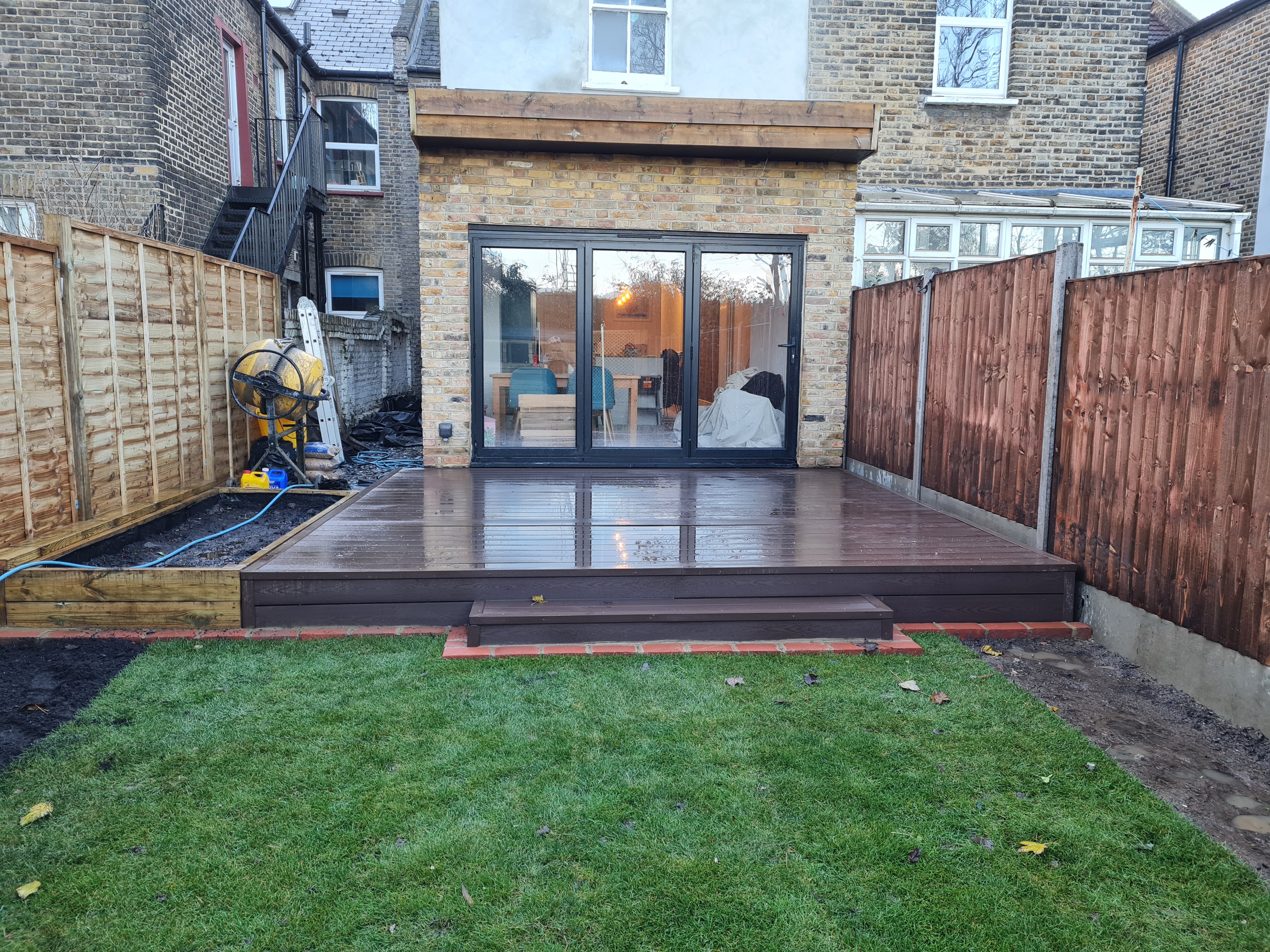 The same rear garden after landscaping with new decking, fencing and fresh turf