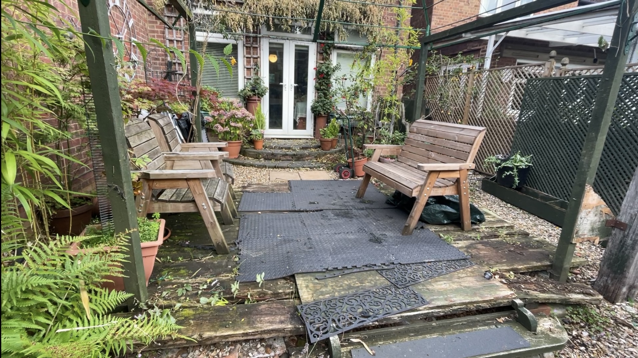 Rear garden before work with worn decking and temporary floor mats